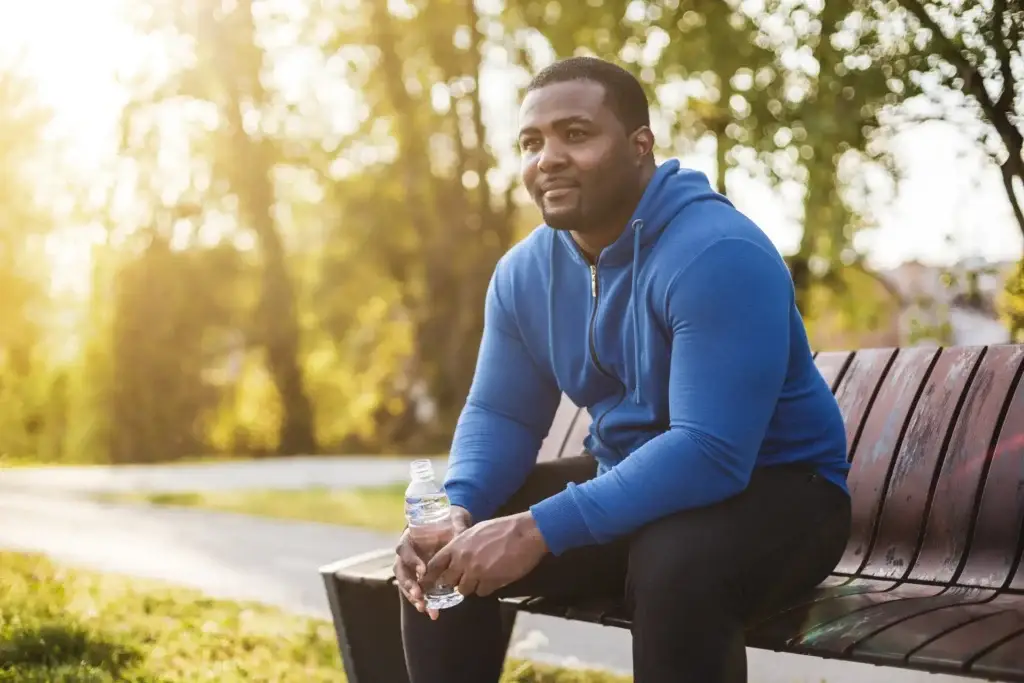 person drinking water on a bench