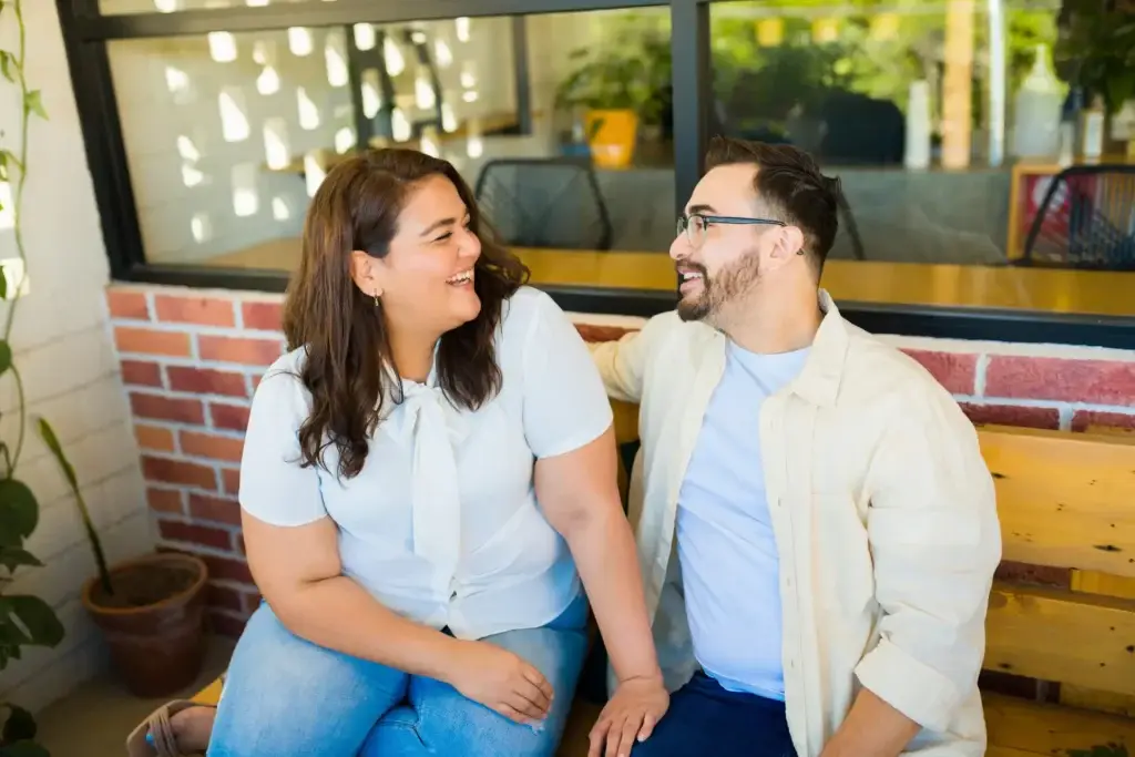 couple sitting on a bench laughing and smiling at eachother
